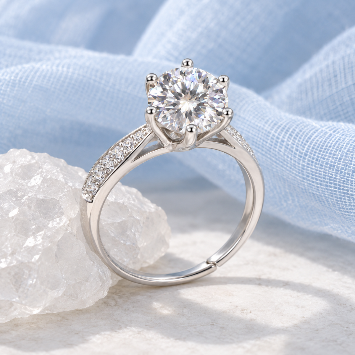 NEARHELD six-prong moissanite ring beside white quartz and pale blue gauze