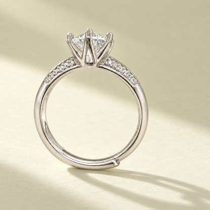 Side profile of the NEARHELD moissanite crown ring on a warm cream surface