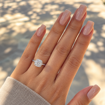 Round moissanite cushion halo ring worn on a hand in natural daylight.