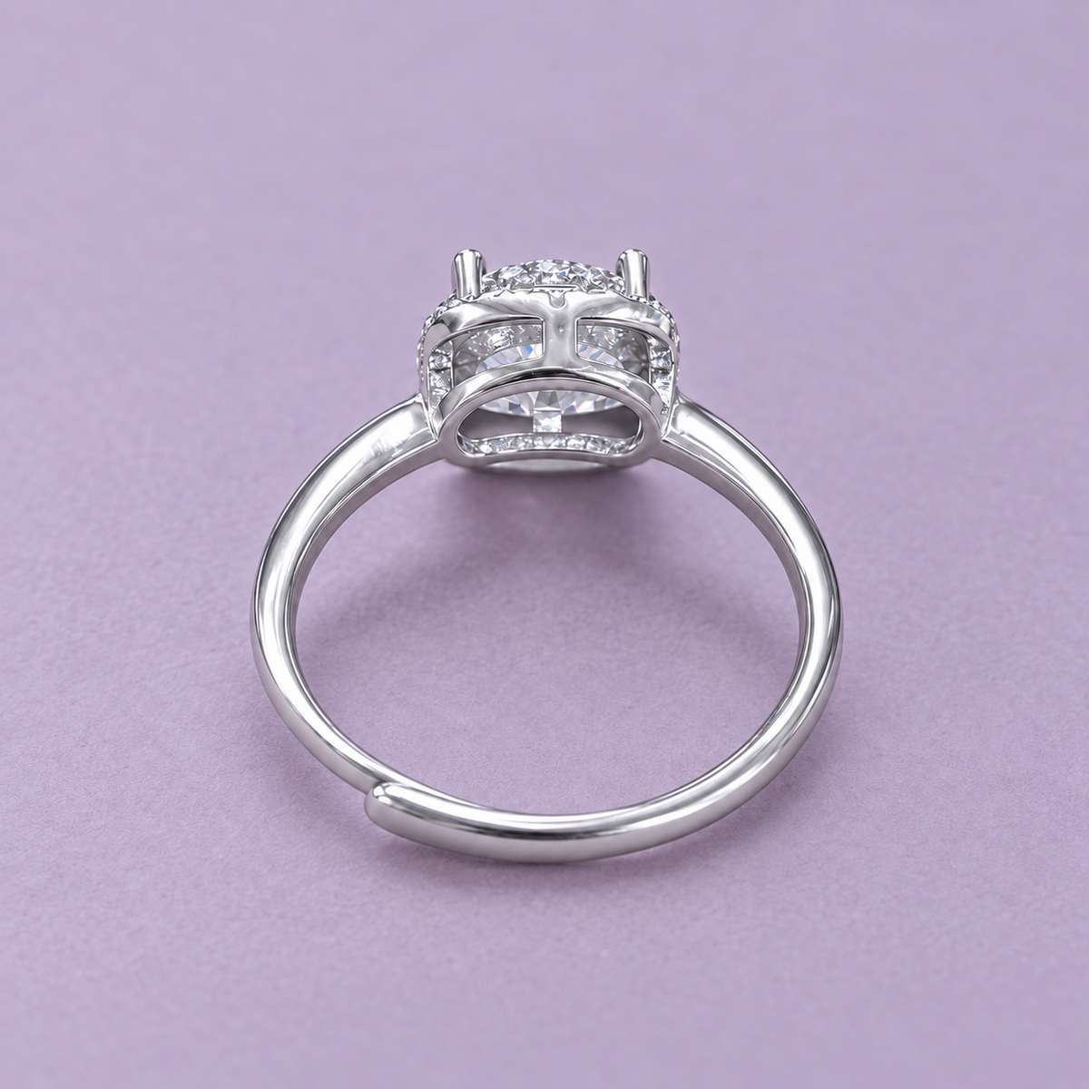 Underside view of the silver halo ring showing the curved basket and adjustable opening on a pale lilac surface.