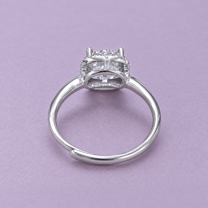 Underside view of the silver halo ring showing the curved basket and adjustable opening on a pale lilac surface.