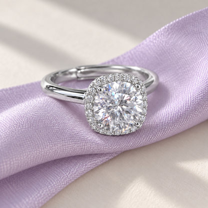 Round moissanite cushion halo ring resting on a pale lilac ribbon.