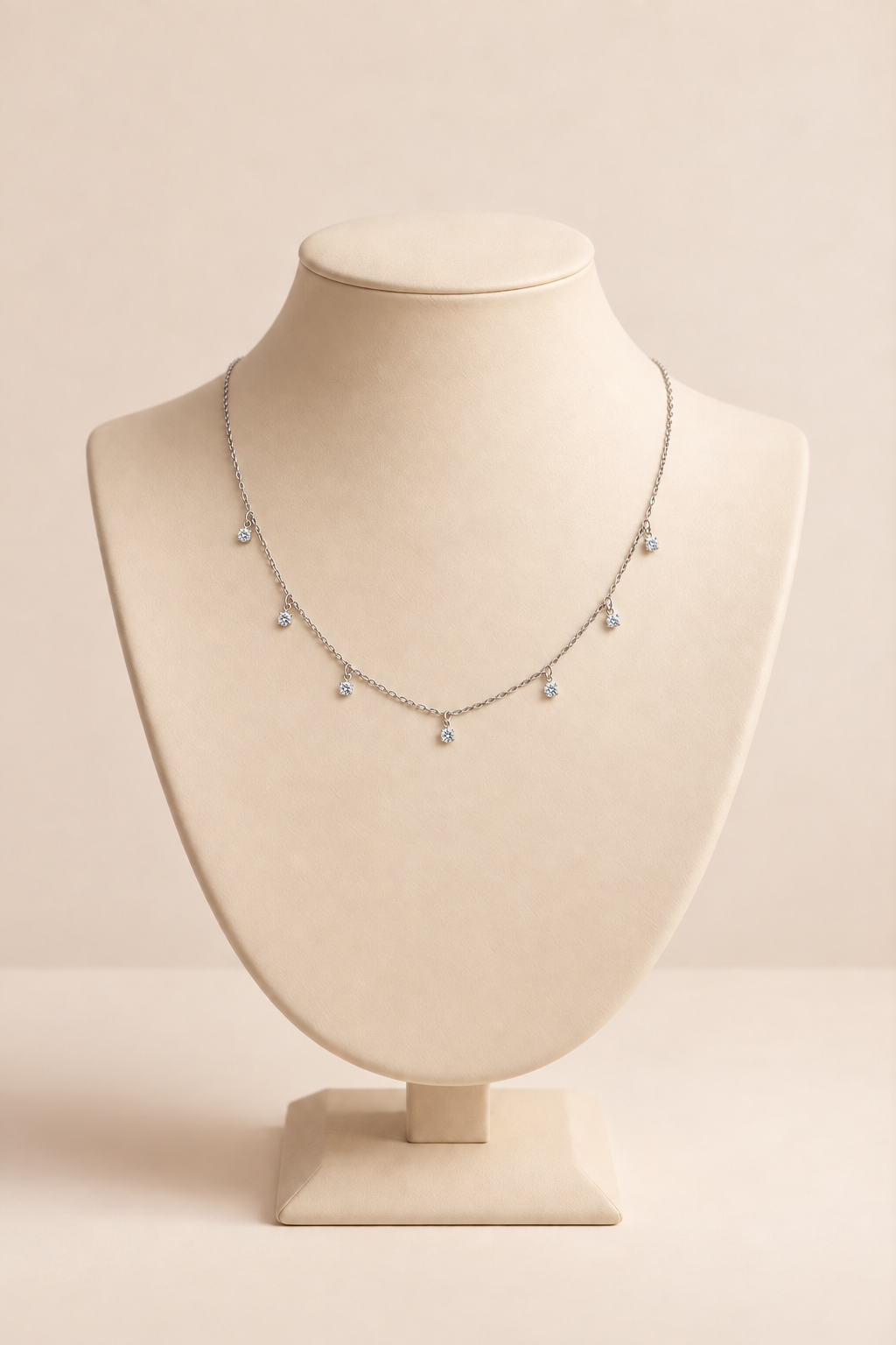 Seven-stone moissanite sterling silver necklace on a beige jewelry display bust