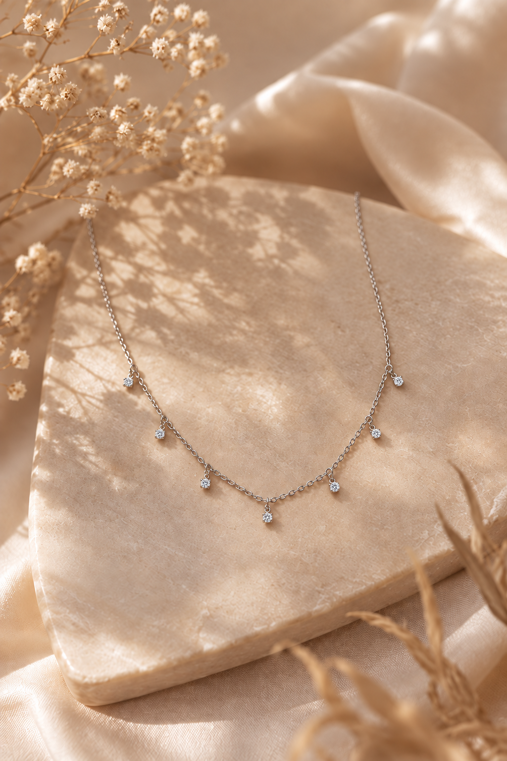 Seven-stone moissanite sterling silver necklace arranged on a sunlit beige surface
